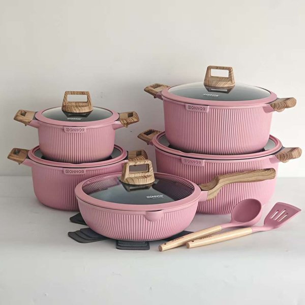 Pink ribbed ceramic-coated cookware set with glass lids and wood-style handles, including pots, pan, and cooking utensils.
